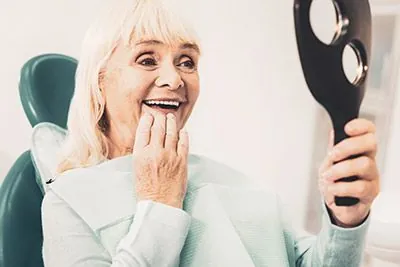 woman loving the look of her dental implants while looking in the mirror