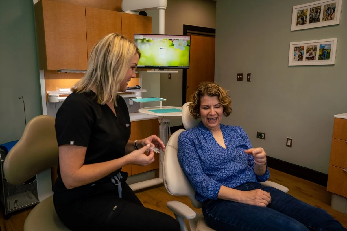Dr. Lynn Booth explaining how a restoration works to a female patient sitting in dental chair